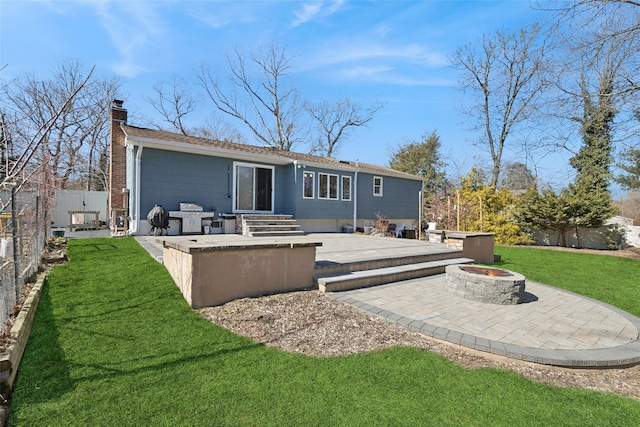 back of property with a patio, a fire pit, fence, a lawn, and a chimney