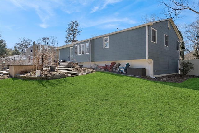 rear view of property featuring a chimney, fence, and a yard