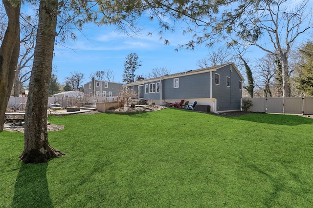 rear view of house with a gate, a fenced backyard, and a lawn