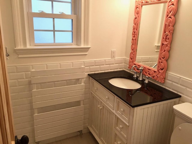 bathroom with a wainscoted wall, vanity, and toilet