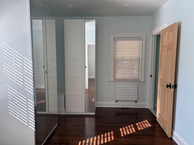 unfurnished bedroom featuring wood finished floors, visible vents, and baseboards