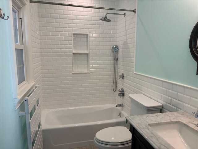 bathroom featuring tile walls, bathtub / shower combination, toilet, wainscoting, and vanity