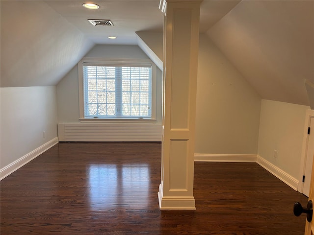 bonus room featuring dark wood-style flooring, visible vents, vaulted ceiling, and baseboards