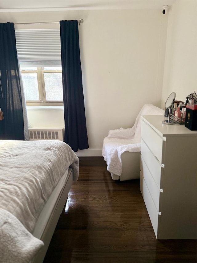 bedroom featuring dark wood-style floors, radiator, and baseboards