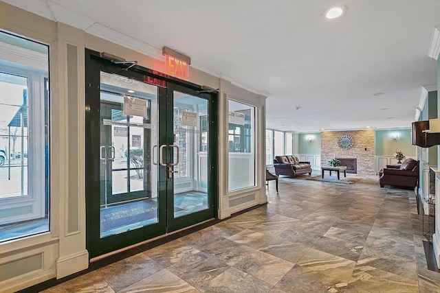 entryway with a large fireplace, french doors, and crown molding