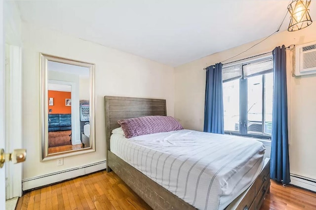 bedroom with baseboard heating, wood finished floors, and a wall mounted AC