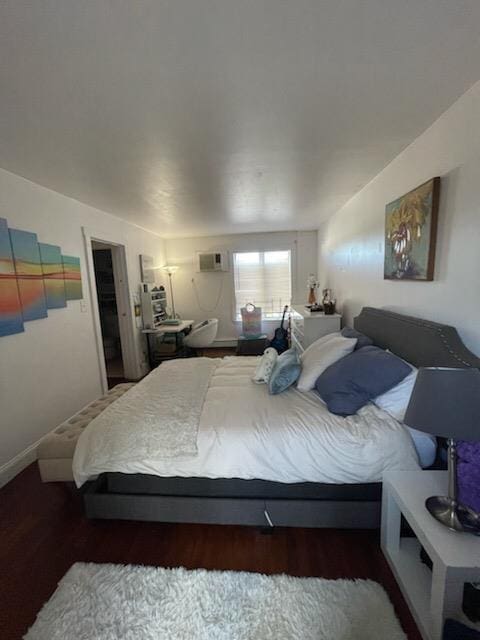 bedroom featuring a wall mounted AC and dark wood finished floors