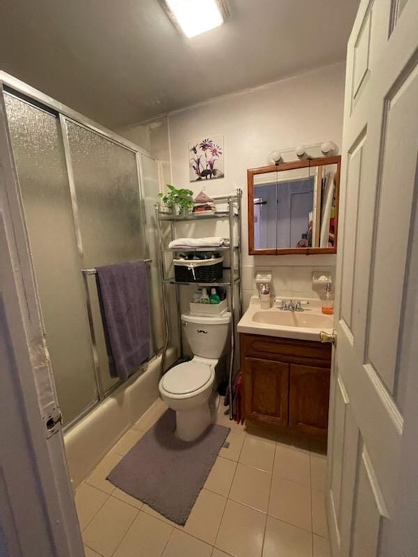 bathroom with tile patterned flooring, vanity, toilet, and bath / shower combo with glass door