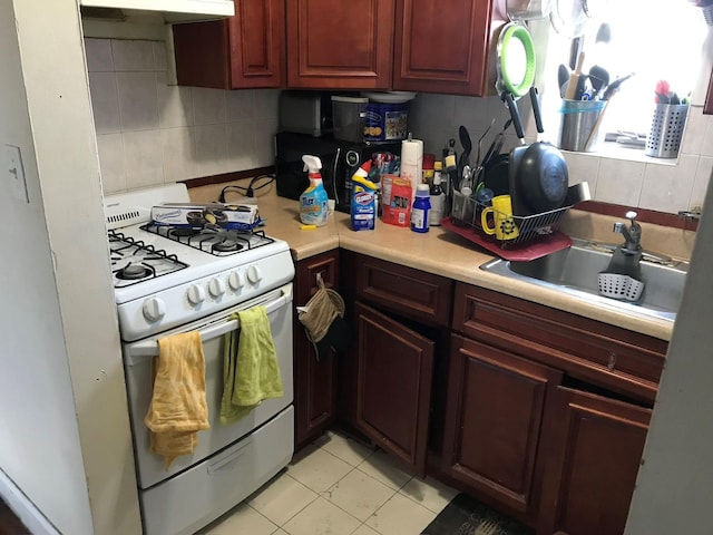 kitchen featuring a sink, white range with gas cooktop, light countertops, dark brown cabinets, and decorative backsplash