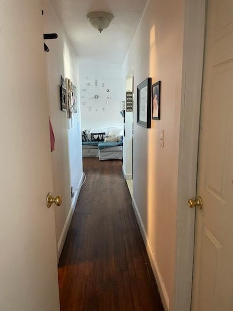 hall with dark wood-style flooring and baseboards