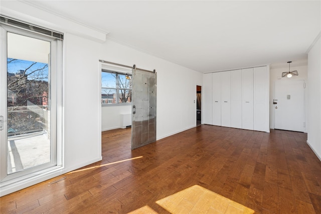 empty room with dark wood-style flooring, crown molding, and baseboards