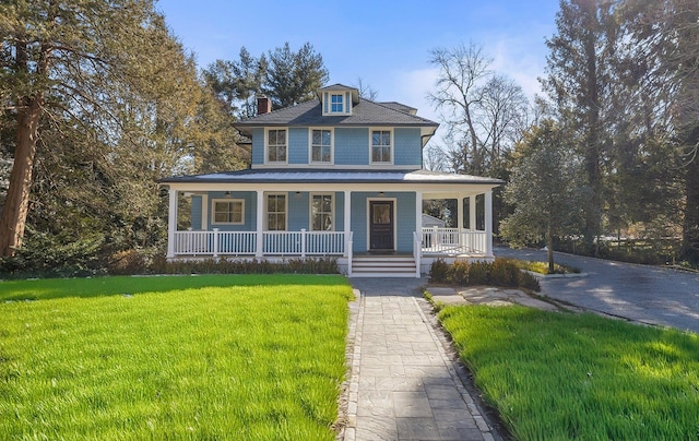 view of front facade featuring covered porch, a chimney, and a front lawn