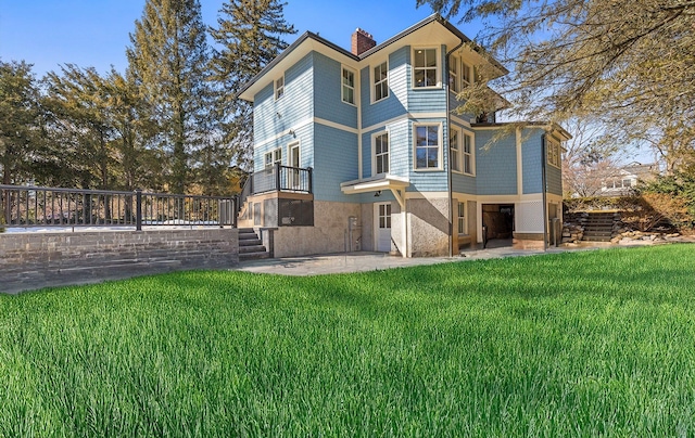 rear view of property with a lawn, a chimney, and a patio