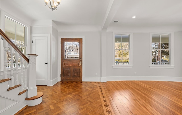 entrance foyer featuring stairs, plenty of natural light, visible vents, and baseboards