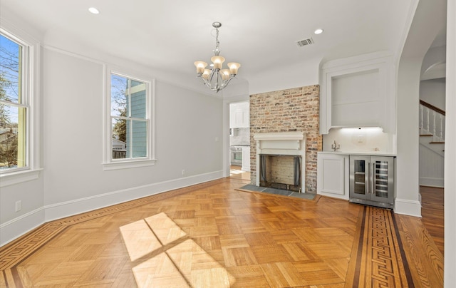 unfurnished living room with a brick fireplace, visible vents, and baseboards