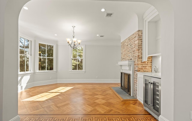 unfurnished living room featuring wine cooler, arched walkways, visible vents, a brick fireplace, and baseboards