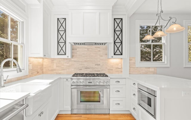 kitchen featuring stainless steel appliances, white cabinetry, backsplash, light stone countertops, and pendant lighting