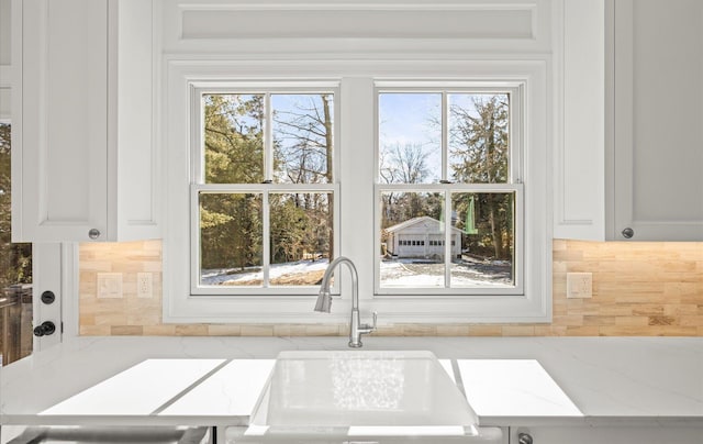 room details featuring light stone counters, a sink, and backsplash