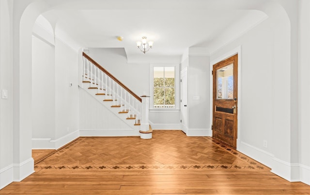 foyer entrance with stairs, baseboards, parquet flooring, and a notable chandelier