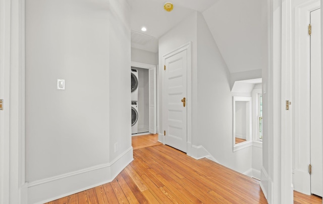 corridor with baseboards, recessed lighting, light wood-type flooring, and stacked washer / drying machine