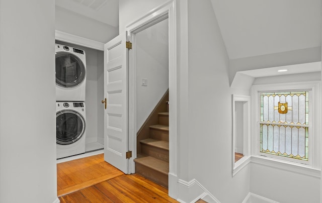 laundry room featuring laundry area, baseboards, stacked washer / dryer, and wood finished floors