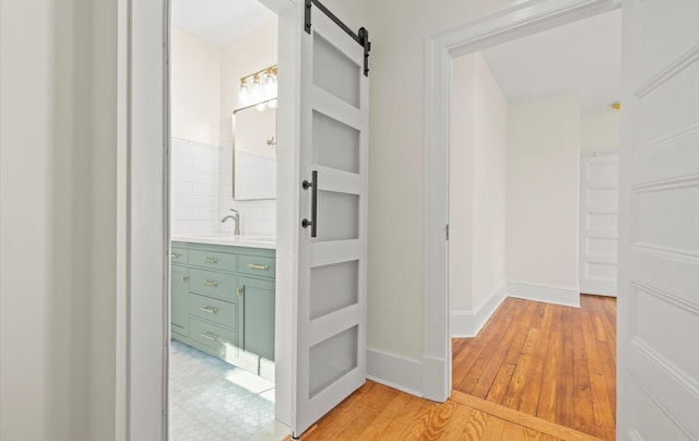 interior space with a barn door, light wood-type flooring, a sink, and baseboards