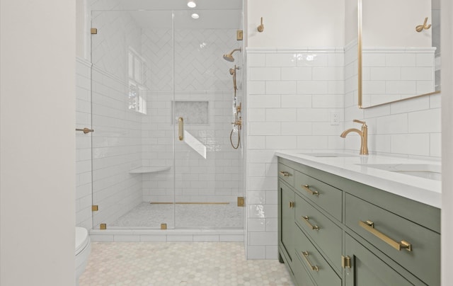 bathroom featuring double vanity, a stall shower, tile walls, toilet, and a sink