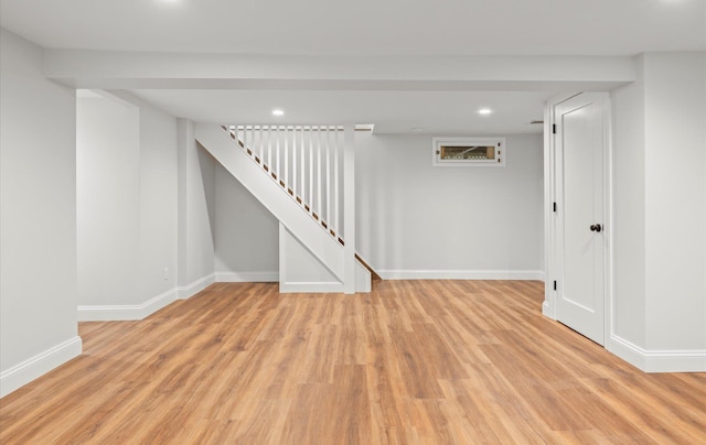 finished below grade area with light wood-style floors, recessed lighting, baseboards, and stairs