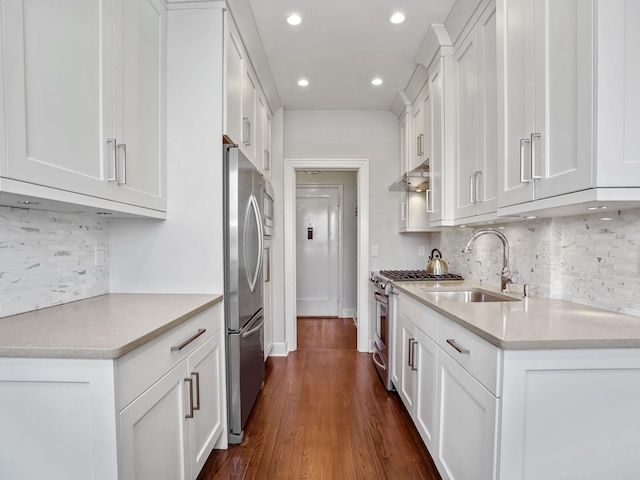 kitchen featuring under cabinet range hood, dark wood-type flooring, a sink, white cabinets, and appliances with stainless steel finishes