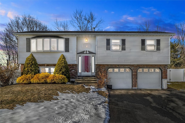 bi-level home featuring brick siding, driveway, and an attached garage