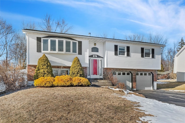 split foyer home featuring driveway, brick siding, and an attached garage