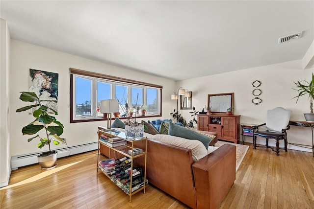 living area with baseboard heating, light wood-type flooring, and visible vents