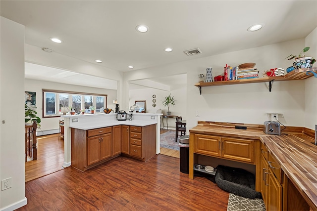 kitchen featuring dark wood-style floors, butcher block counters, brown cabinetry, and visible vents