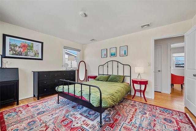 bedroom featuring multiple windows, visible vents, and light wood-style floors