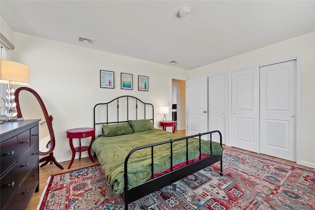 bedroom featuring light wood-style flooring, a closet, visible vents, and baseboards