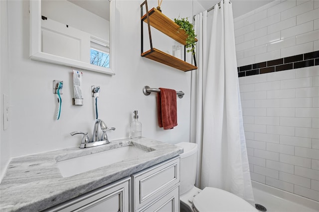 bathroom featuring toilet, tiled shower, and vanity