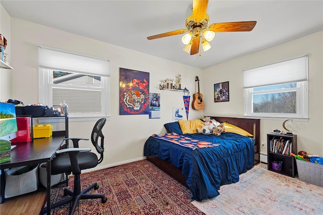 bedroom featuring wood finished floors, a ceiling fan, and baseboards