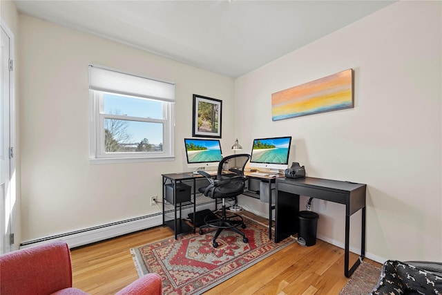 home office with a baseboard heating unit, wood finished floors, and baseboards