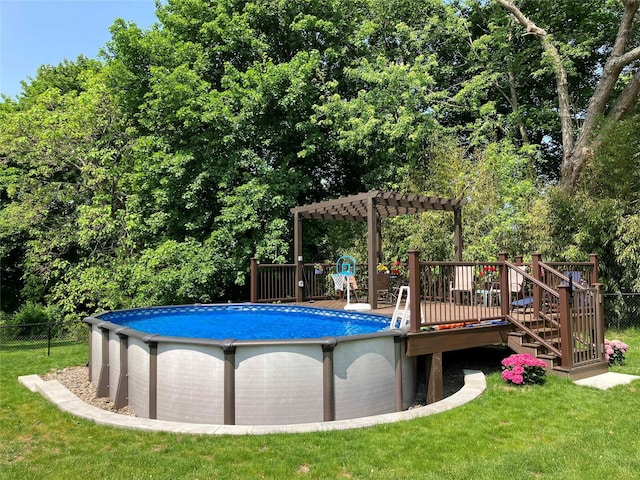 pool with a wooden deck, fence, a pergola, and a yard