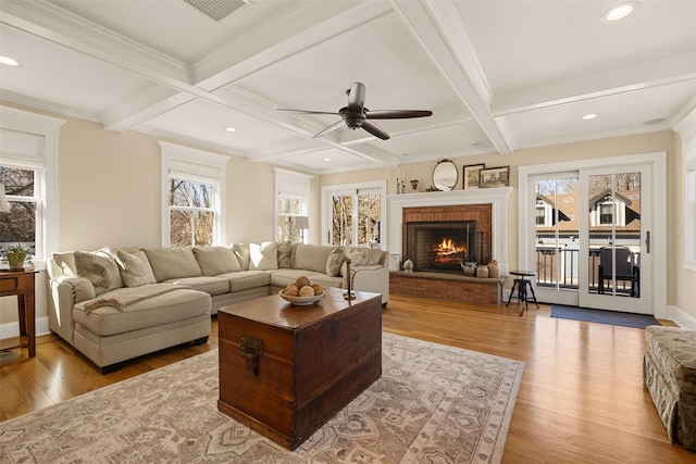 living area featuring a fireplace, beam ceiling, a wealth of natural light, and wood finished floors