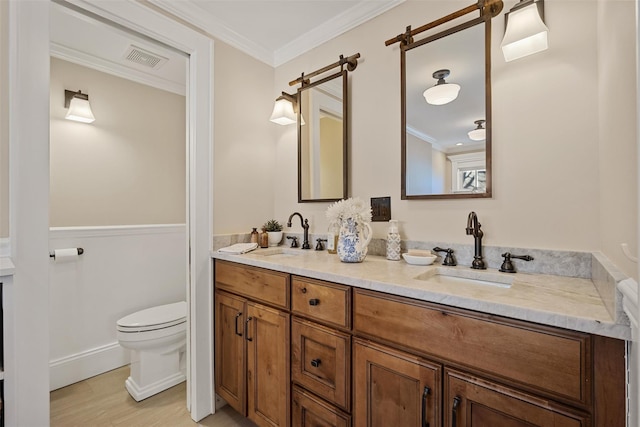 full bath featuring toilet, crown molding, visible vents, and a sink