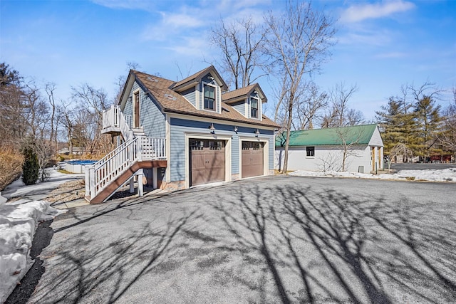 view of home's exterior featuring an attached garage, stairway, and aphalt driveway