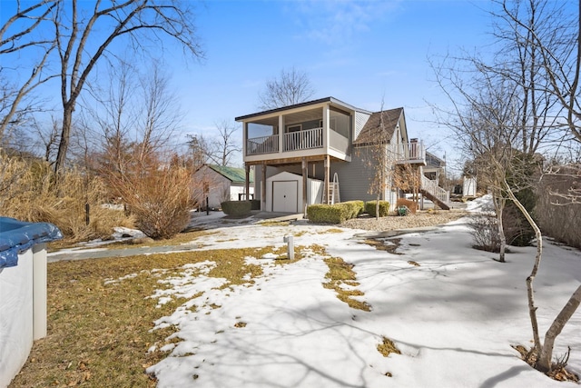 view of front of house with a garage, a sunroom, driveway, and stairway