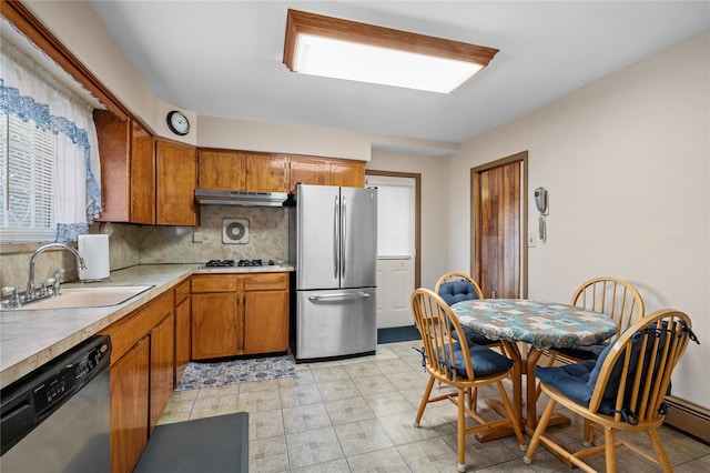 kitchen featuring under cabinet range hood, a sink, light countertops, appliances with stainless steel finishes, and brown cabinetry