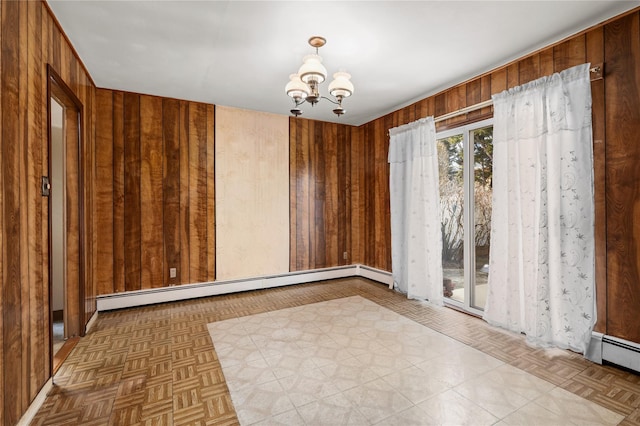 empty room with a chandelier, a baseboard radiator, and wood walls