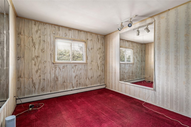 unfurnished room featuring plenty of natural light, a baseboard heating unit, dark colored carpet, and track lighting