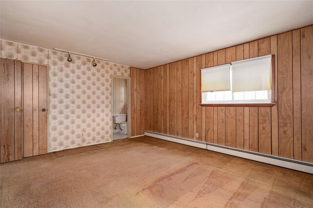 unfurnished room featuring rail lighting, carpet, and a baseboard heating unit