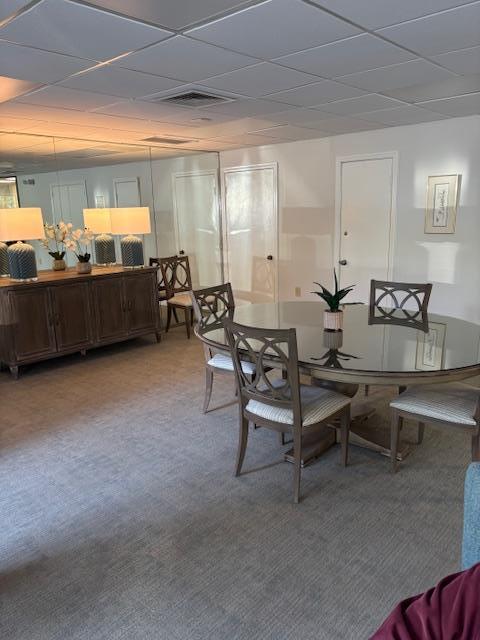 carpeted dining room with a drop ceiling and visible vents