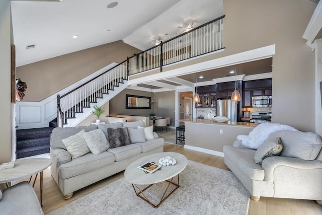 living room featuring light wood finished floors, visible vents, stairway, high vaulted ceiling, and recessed lighting