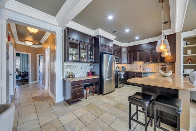 kitchen featuring visible vents, appliances with stainless steel finishes, a breakfast bar, light stone counters, and pendant lighting